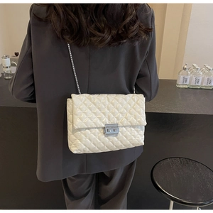 Detail of white quilted chain bag with silver twist lock and glossy patent finish