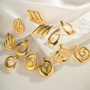 Detailed view of polished gold geometric earrings on elegant white silk and stone