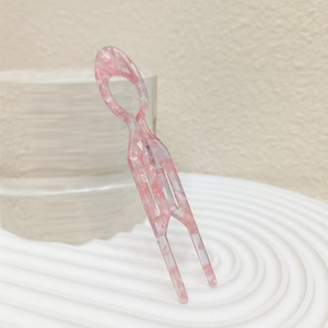 Macro detail of U-shaped hair fork in pink marble acetate for elegant bun hairstyles