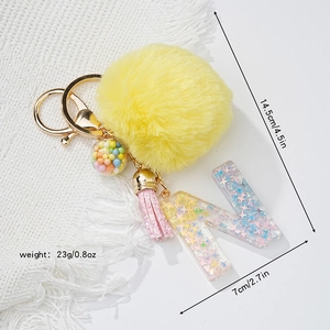 Detail view of yellow pompom keychain with resin letter N and dimensions in inches