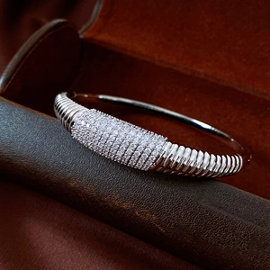 Dettaglio macro di un bracciale rigido argento a righe con cristalli su pelle