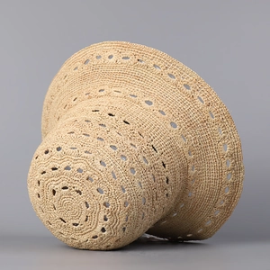 Détail d'un chapeau de paille beige tissé main avec des motifs circulaires ajourés