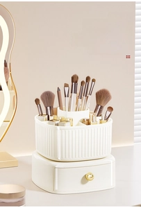 Rotating ivory makeup organizer with top brush holder and bottom drawer with gold handle