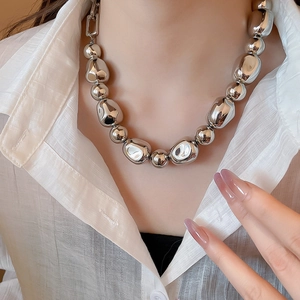 Vue détaillée du collier en perles argentées irrégulières sur une chemise blanche chic
