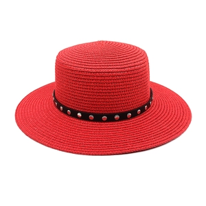 Détail d'un chapeau de paille rouge à toit plat avec ruban à rivets pour l'été