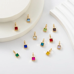 Collection of colorful birthstone pendants with gold plating on white geometric props