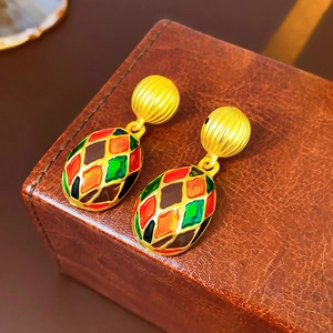 Macro shot of vintage gold earrings with colorful enamel diamond pattern and metallic beads