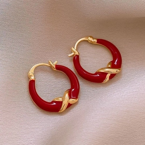 Minimalist red heart gold earrings with twist design on light beige background