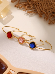 Detailed view of faceted glass crystals on three-piece gold-plated open bangles