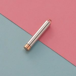 Detailed close-up of a silver cylindrical pendant with elegant rose gold accents