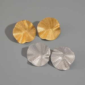Detail view of large wrinkled texture metal earrings in gold and silver finish
