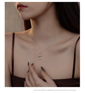 Detail of S925 silver bear pendant necklace with a pink star on a woman's collarbone