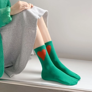 Grass green mid-calf crew socks with a vibrant red heart pattern in soft cotton knit