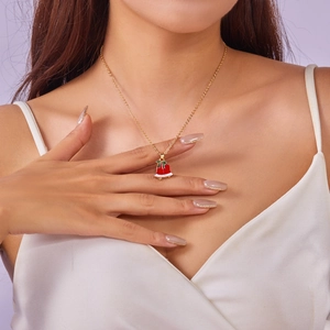 Detail of a Christmas bell pendant necklace in red and white enamel on a gold chain