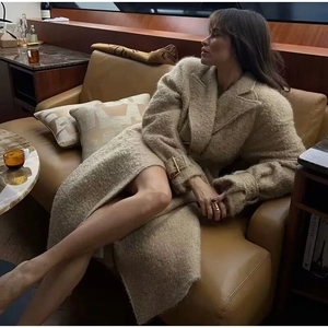 Detail of elegant beige faux shearling long coat featuring golden metal belt buckle