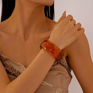 Close-up of a vintage amber resin bangle with marbled texture worn on a model wrist