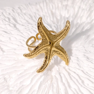 Golden starfish open ring with hammered texture on white coral background