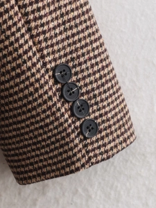 Detailed close-up of houndstooth wool coat cuffs with four black decorative buttons