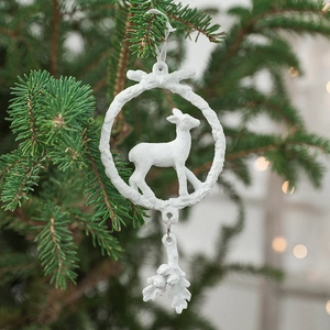 White reindeer wreath ornament with gold accents hanging on a green Christmas tree branch