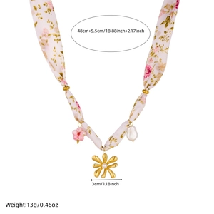 Close-up of pink floral fabric chain with gold flower pendant and white pearl detail