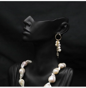 Detail of baroque pearl tassel earrings and matching necklace on black mannequin display