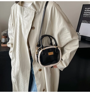 Detail of black leather crossbody bag with white faux fur trim and gold metal logo