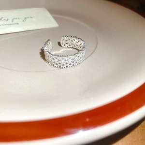 Detailed close-up of zircon lace floral ring with intricate woven silver textures