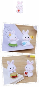 Close-up of cute white resin rabbit figurines with juice and carrot on office desk