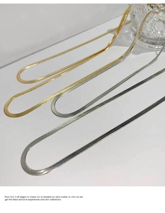 Close-up of four minimalist snake bone flat chains in polished gold and silver finishes