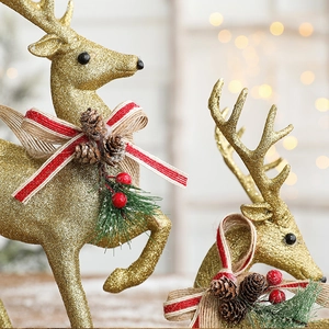 Sparkling gold reindeer Christmas ornament with red pine cone bow and festive bokeh lights