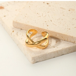 Detail of gold geometric cross ring on beige travertine stone with minimalist aesthetics