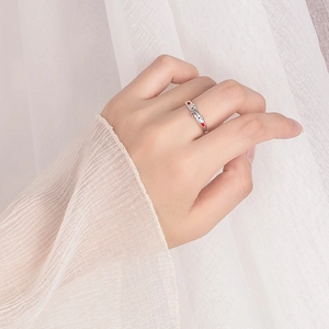 Silver pig ring with red and white gems shown on hand with elegant white background