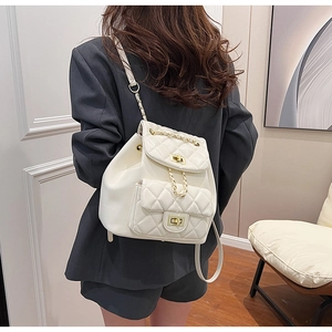 Close-up of white quilted backpack with gold turn-lock and leather-woven chain straps