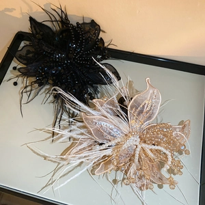 Close-up of elegant fabric butterfly hair claw with pearls and feathers in champagne gold