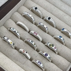Silver hollow wavy geometric open rings with colorful gemstones in a beige display box