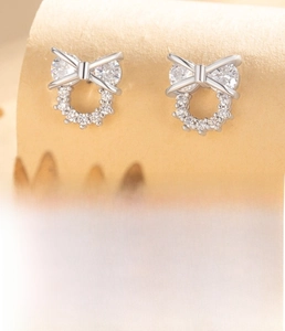 Detailed view of silver bow earrings with micro zircons and technical measurements
