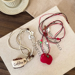 Detail of handmade fabric coffee cup and red apple pendants with wooden beads and colorful cord
