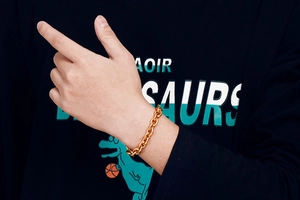 Close-up of a gold oval link chain bracelet worn on a wrist with casual clothing