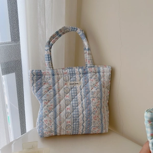 Close-up of quilted floral plaid tote bag with blue rabbit patterns and fabric label