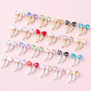 Vue macro de 24 bijoux d'ongles en forme de nœud métallique avec strass cœur colorés
