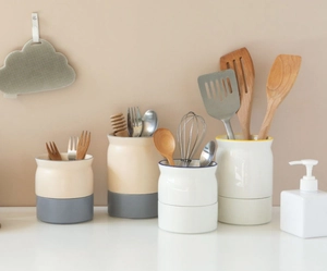 Ceramic utensil holders with draining base storing wooden spoons and kitchen tools