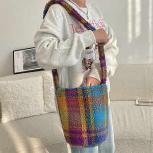 Detail of colorful plaid faux fur bucket bag with wide plush strap for autumn fashion