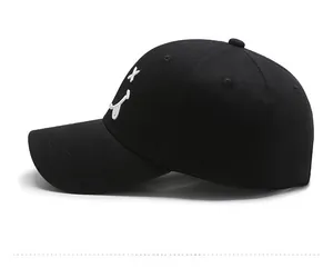 Detail of white embroidered smiley face on side of black cotton twill baseball cap