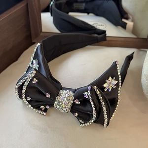 Macro view of black satin headband featuring luxury rhinestone bow and shiny crystals