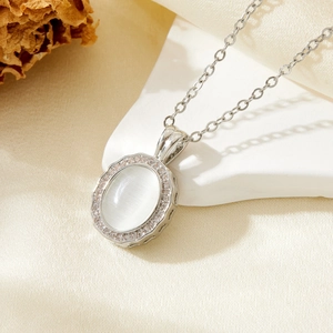 Macro detail of silver drop pendant with white cat eye stone and zircon borders