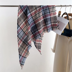 Detail of checkered triangle scarf with tassels in blue, brown, and red plaid pattern