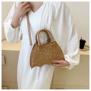 Detail of brown bat-shaped tote with spider web embroidery and gold-tone metal hardware