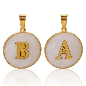 Detailed macro view of gold-plated stainless steel initial charms with white shell inlay