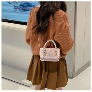 Pink tweed kids crossbody bag with pearl handle and metal chain shown on model