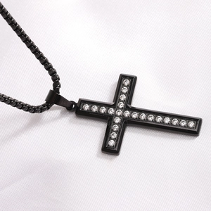 Macro shot of black stainless steel cross necklace with shimmering crystal stones inlay